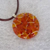 Autumn time round pendant, shades of orange, yellow and white, with pendant at an angle.
