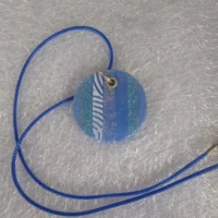 Round blue pendant with stripes of sparkle in the dichroic glass, stripe of dichroic glass showing flashes of gold and pink, also a strip of blue and white screen printed glass. 925 sterling silver grommet and jump ring, and hangs from a blue cord necklace.