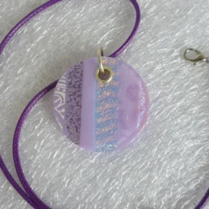 Lilac dichroic glass round pendant showing vertical stripes of pattern dichroic glass, white & lilac glass, and iridised glass. Flashes of blue and gold can be seen in the dichroic glass.
