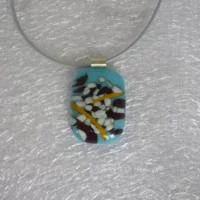 Unusual fused glass blue and white pendant with colours of brown and tan on top. Hangs from a grey cord necklace. 925 sterling silver bail attached.