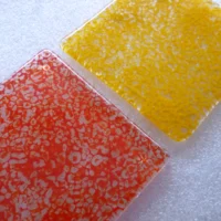 Close up of red and yellow fused glass coasters from a different angle showing mottled effect