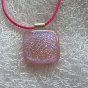 Close up of sparkly pink dichroic glass pendant with 925 sterling silver bail and bright pink cord necklace.