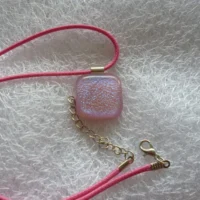 Square pink dichroic glass pendant with pink cord necklace.