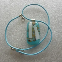 Turquoise & white reactive glass pendant with brown and silver pattern with 925 sterling silver bail and hangs from a blue cord necklace.