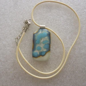 Cream pendant with turquoise and silver pattern on top, 925 sterling silver bail and hangs from a cream cord necklace.