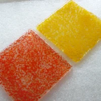 Two fused glass coasters in red and yellow from a different angle
