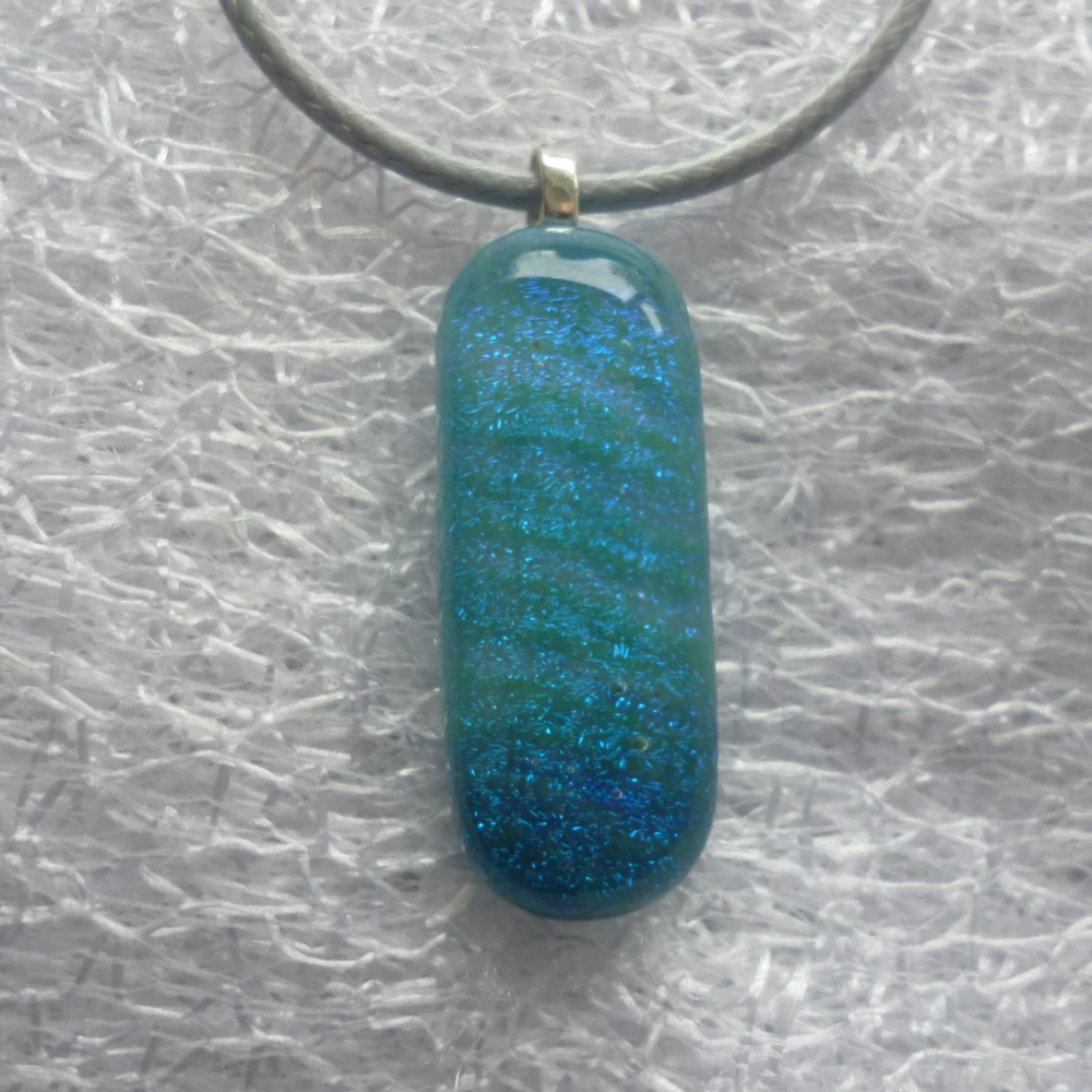 Close up of sparkly blue dichroic glass pendant with rounded corners