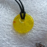 Close up of yellow donut pendant with a hole for cord to be threaded through.