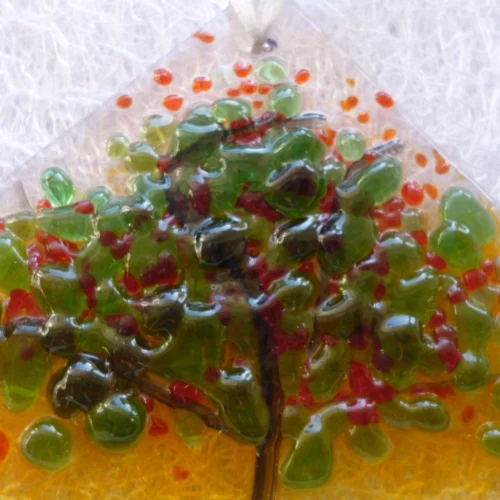 Close up of small suncatcher with summer inspired colours of red and green in the design of a tree. This suncatcher is a very tactile design.