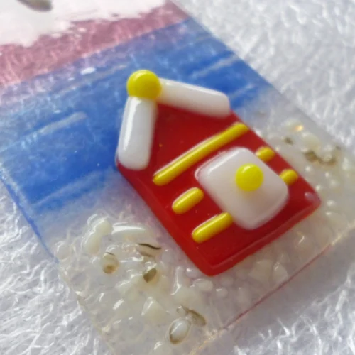 Close up and side view of small suncatcher. Red coastal beach hut with yellow strips. This is a very tactile design.