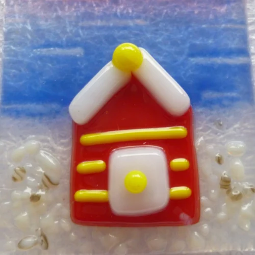 Close up of red beach hut with yellow stripes, white door with yellow handle, white trimmed roof.