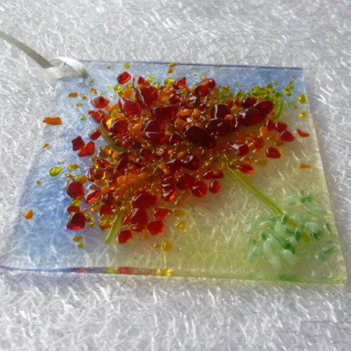 Side view of the suncatcher showing the tactile leaves made with glass frit in colours of red, orange and yellow.