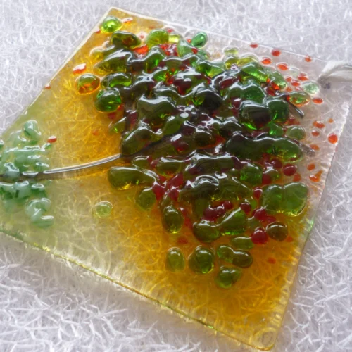 Side view of summer inspired small suncatcher with colours of red, green and orange.