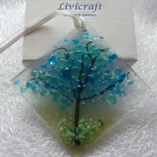 Blue winter tree suncatcher leaning against a white gift box.