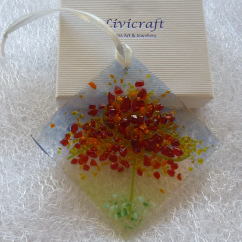 Small suncatcher leaning against a Livicraft gift box. Autumn designed tree fused on to a diamond shaped piece of glass.