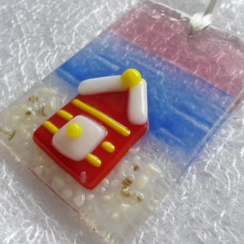 Side view of tactile small suncatcher with red beach hut fused on top. Hut has yellow stripes and white door.