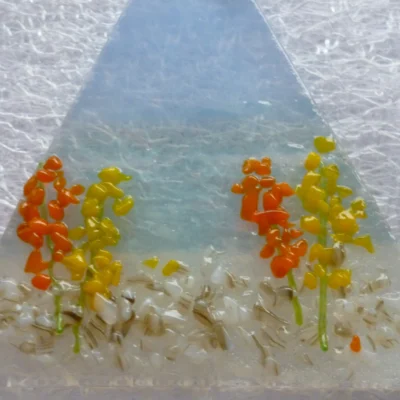 Close up of coastal suncatcher with orange flowers and blue background. This is a very tactile design.
