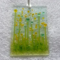 Rectangle fused glass suncatcher with yellow and green transparent beads for flowers with green stringer stems. Yellow and green frit used for decoration and hangs from a white ribbon.
