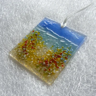 Side view of square coastal suncatcher hanging from a white ribbon.