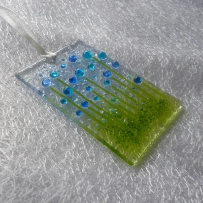 Side view of tactile fused glass suncatcher with blue flowers