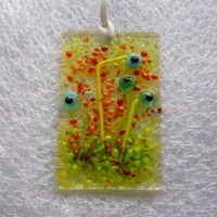 Small rectangle fused glass flower suncatcher with quirky flowers using a square glass with black centres and green stems. Hangs from a white ribbon.