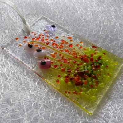 Side view of tactile pink and lilac flower suncatcher, hanging from a white ribbon.