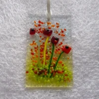 Rectangle fused glass red flower suncatcher hanging from a white ribbon threaded through to hang from. Frit added for decoration.