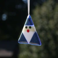 Triangle shaped blue fused glass Santa with white beard and red nose, hanging from a white ribbon.