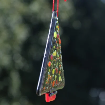 Side view of glass Christmas tree hang from a red ribbon.