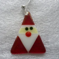 Quirky red iridised glass Santa in a triangular shape, with a white beard and red nose hanging from a white ribbon with a small novelty bell. The irid glass gives Santa a little bit of a shimmer