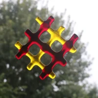 Red and yellow fused glass suncatcher in a lattice design hanging from a clear cord