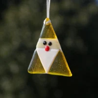 Triangle shaped fused glass yellow gonk with a white beard and red nose, hanging from a white ribbon.