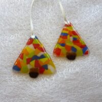 Two colourful fused glass Christmas trees laying on a white cloth.