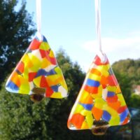 Two fused glass colour Christmas trees hanging from white ribbons. Trees are triangle shaped with colours of red, yellow, orange, green, blue and white.