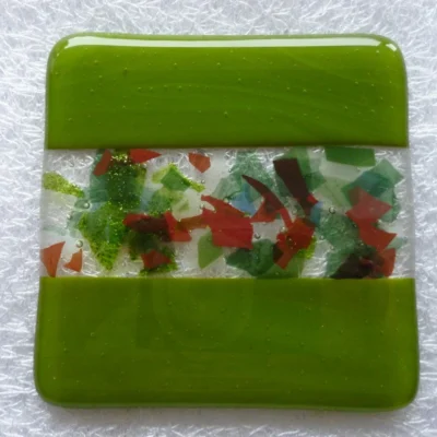 Refreshing green handmade fused glass coaster with decorative centre strip made with colourful confetti glass in red, green, white and blue.