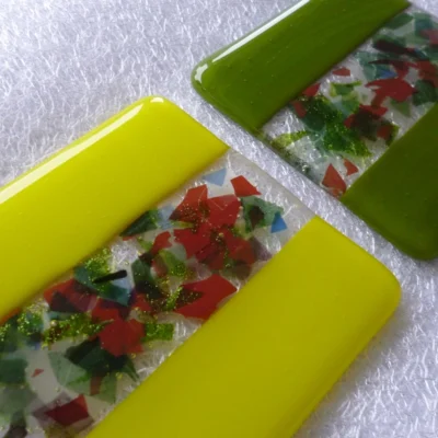 yellow and green decorative handmade fused glass coasters laying at an angle.