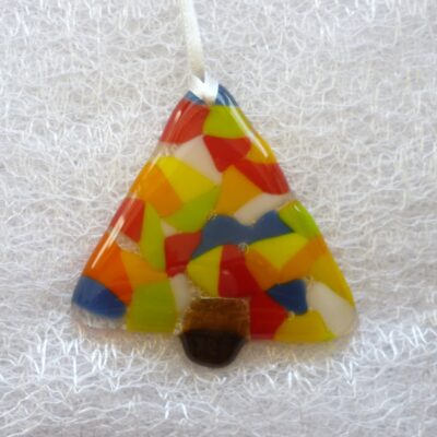 Small single fused glass colourful Christmas tree laying on a white cloth.