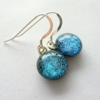 Close up of blue teal dichroic glass earrings.
