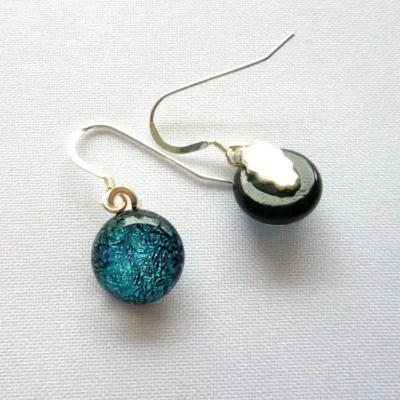 Handmade teal blue cabochons with silver plated bails attached, hanging from 925 sterling silver ear hooks. On earring is showing front of cabochon and the other showing silver plated bail.