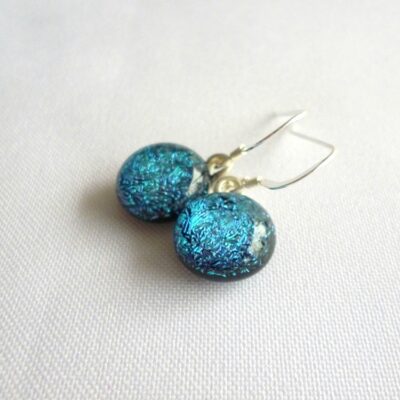 Blue teal dichroic glass earrings laying at an angle showing depth