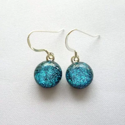 Dichroic glass teal blue cabochon earrings hanging from 925 sterling silver ear wires
