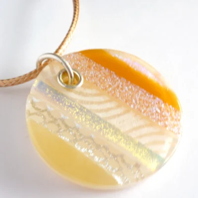 Handmade beige dichroic fused glass pendant with sterling silver fitting on a white background