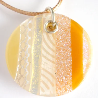 Close up of handmade beige dichroic fused glass pendant with sterling silver fitting