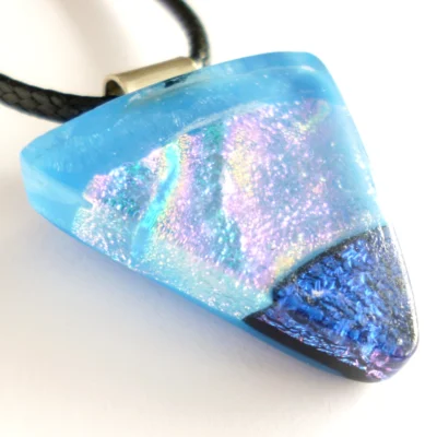Close up of handmade blue dichroic fused glass pendant with sterling silver bail