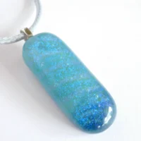 Blue dichroic glass pendant with sterling silver bail on a white background.