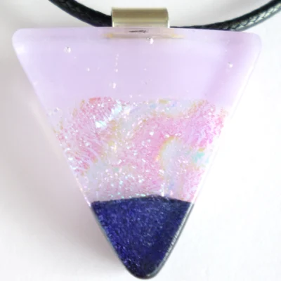 Close up of handmade lilac dichroic fused glass pendant with sterling silver bail