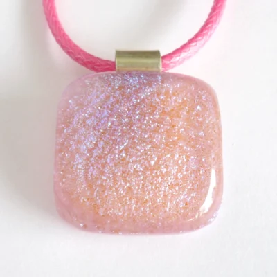 Close up of pink dichroic glass pendant necklace with sterling silver bail and pink cord necklace