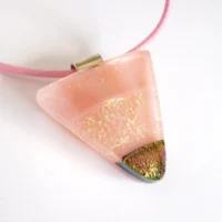 Pink dichroic glass triangular pendant on a cord necklace showing depth of glass