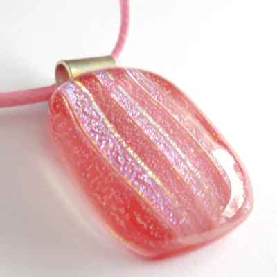 Close up of handmade pink fused glass pendant with sterling silver bail