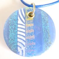 Close up of handmade blue dichroic fused glass pendant with sterling silver fitting